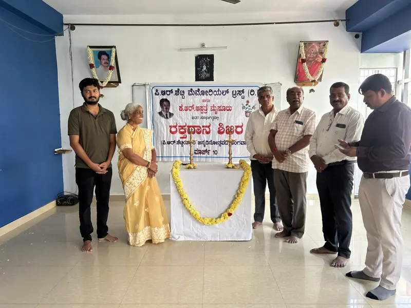 Sujatha R Shetty and guests at the opening of the Trust's blood donation camp, beside the camp banner